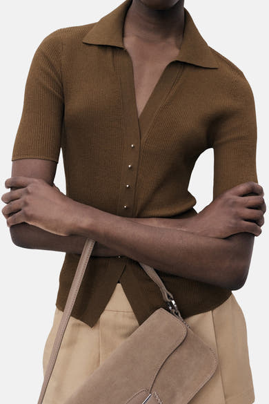 MANGO poloshirt met korte mouwen, ribgebreide textuur, met knopen en gedragen met een beige broek en een handtas.