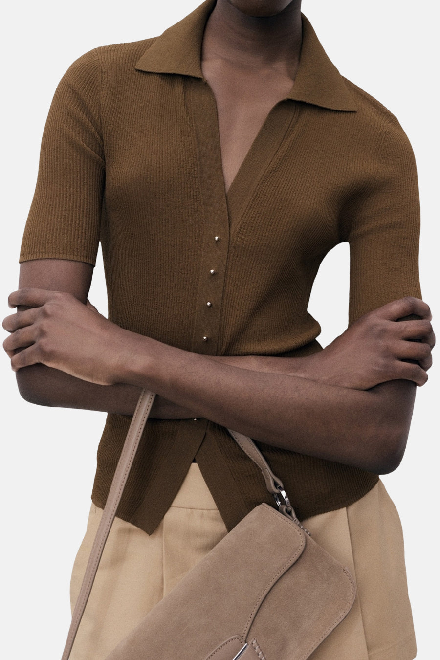 MANGO poloshirt met korte mouwen, ribgebreide textuur, met knopen en gedragen met een beige broek en een handtas.