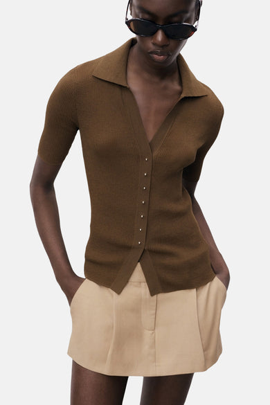 Polo kaki à manches courtes de MANGO, boutonné devant, porté avec un short beige uni.
