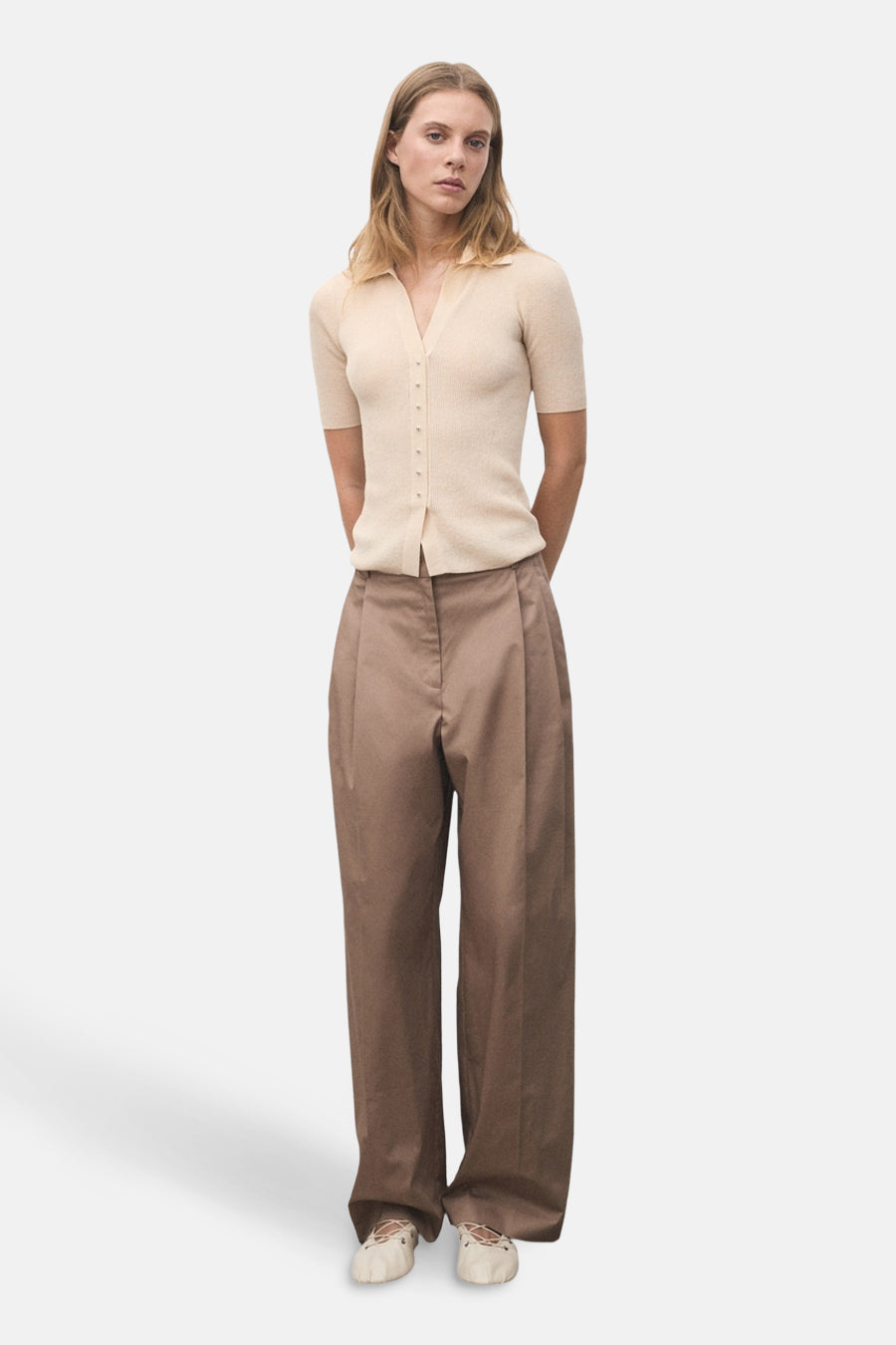 Beige poloshirt met korte mouwen van MANGO, gedragen met een wijde bruine broek en crèmekleurige ballerina's.