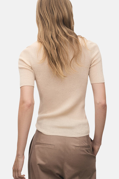 Polo à manches courtes beige de MANGO, porté avec un pantalon marron, vue de dos.