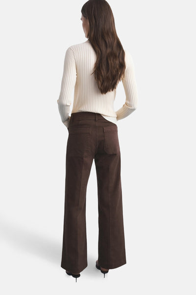 Gekleurde bruine jeans van MANGO, uitlopende pasvorm, met achterzakken en gedragen met een witte trui.