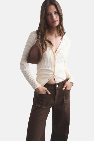 Bruine jeans van Mango, met opgestikte zakken en een relaxte pasvorm, gedragen met een ivoorkleurige gebreide cardigan met knopen.