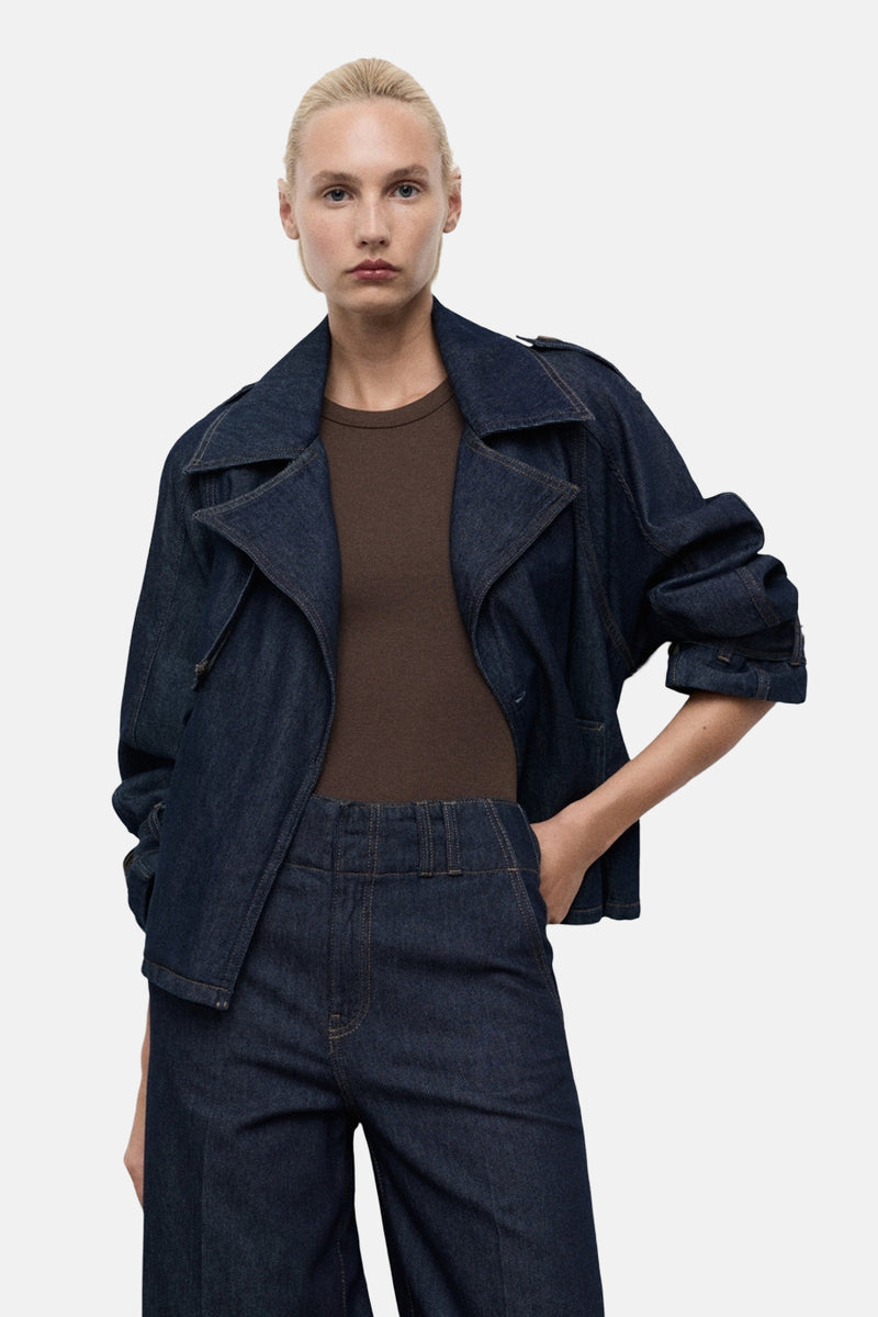 Veste courte en denim bleu foncé de MANGO, portée avec un t-shirt marron et un pantalon taille haute assorti.