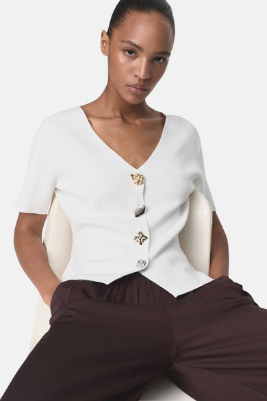 Witte MANGO-cardigan, korte mouwen, gedragen met een bruine broek, achtergezicht.