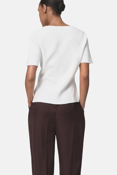 Cardigan blanc de MANGO, manches courtes, porté avec un pantalon marron, vue de dos.
