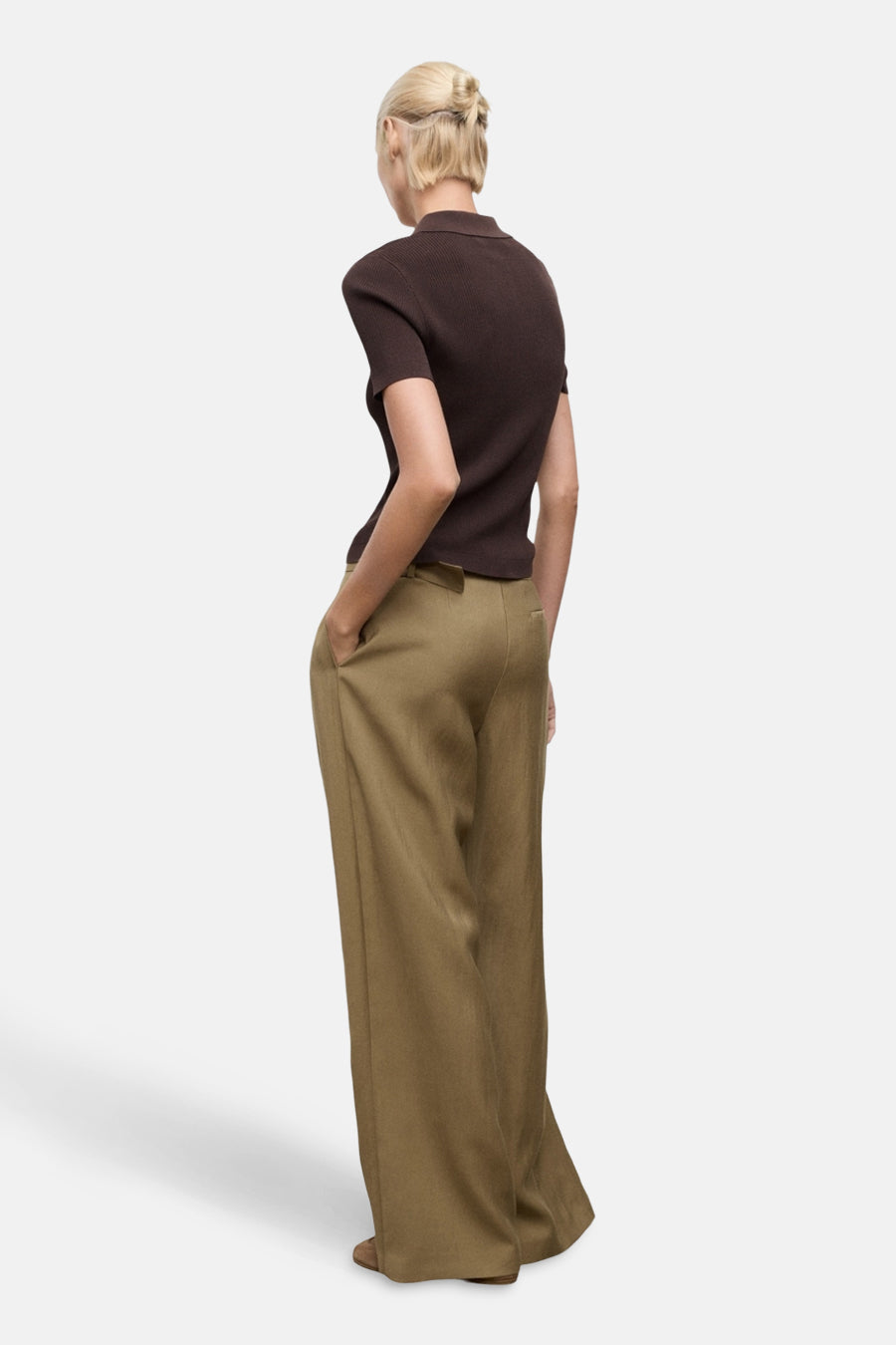Pantalon kaki van MANGO, coupe ample et fluide, porté avec un haut marron et les mains dans les poches.
