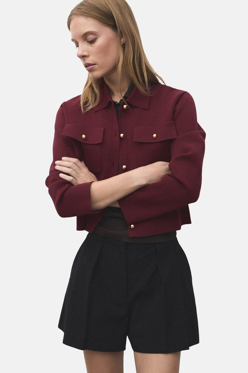 Bordeaux vest van MANGO, gedragen met een zwarte korte broek, van achteren gezien.