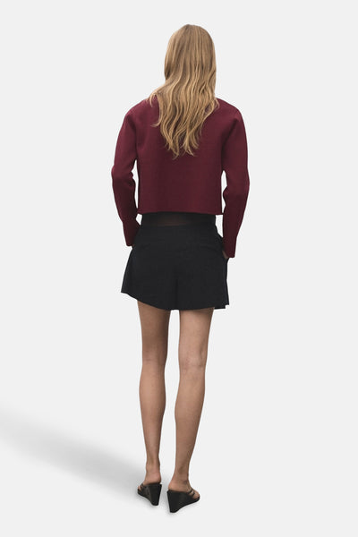 Cardigan bordeaux by MANGO, porté avec un short noir, vue de dos.
