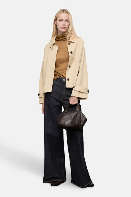 Veste courte beige de MANGO avec boutons marron, portée avec un pull à col roulé marron, un jean large et un sac à main en cuir.
