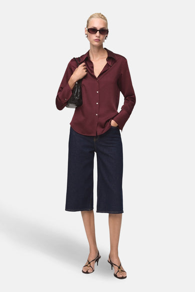 Bordeaux blouse met lange mouwen van MANGO, gedragen met een wijde jeans en zwarte sandalen.
