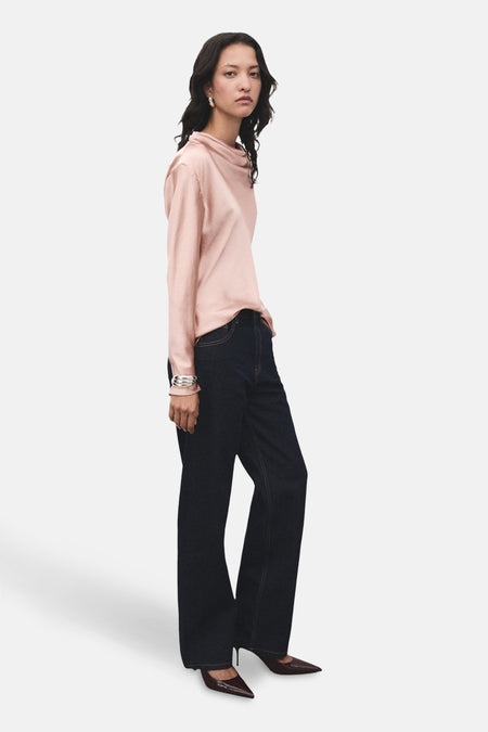 Roze blouse met lange mouwen van MANGO, gedragen met een donkere spijkerbroek en bordeauxrode pumps, zijaanzicht.
