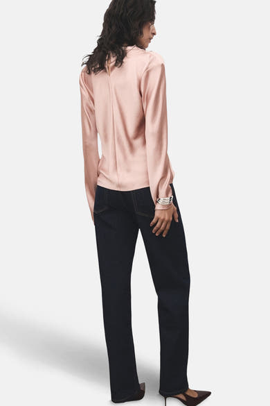 Roze blouse met lange mouwen van MANGO, met geplooide details op de rug, gedragen met een donkere jeans en hakken.