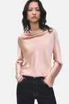 Roze blouse met lange mouwen van MANGO, met een gedrapeerde kraag, gedragen met een spijkerbroek en een zilveren armband.