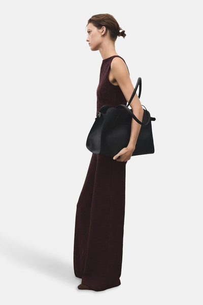 Bordeaux jumpsuit van MANGO, gedragen door een model, met een subtiele textuur en wijde pijpen.