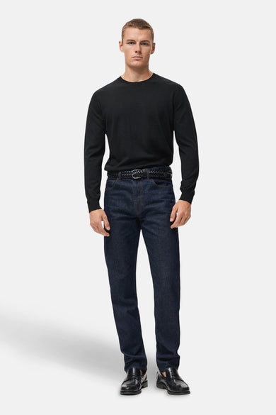 Zwarte rondehals trui van MANGO, gedragen met een donkerblauwe jeans en een gevlochten riem.