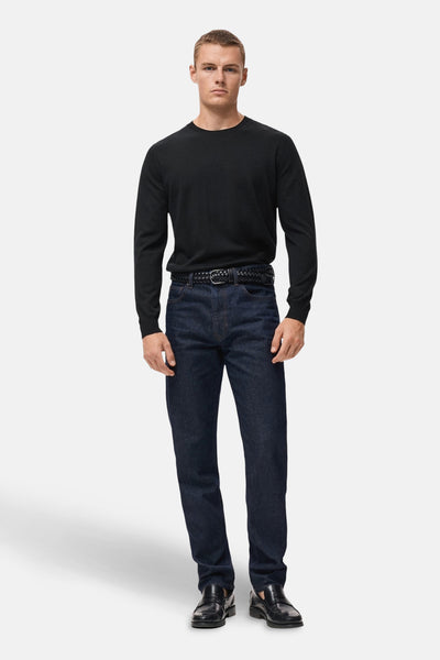 Zwarte rondehals trui van MANGO, gedragen met een donkerblauwe jeans en een gevlochten riem.