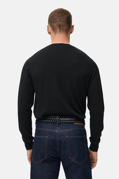 Zwarte rondehals trui van MANGO, gedragen met een donkerblauwe jeans en een zwarte gevlochten riem, achtergezicht.