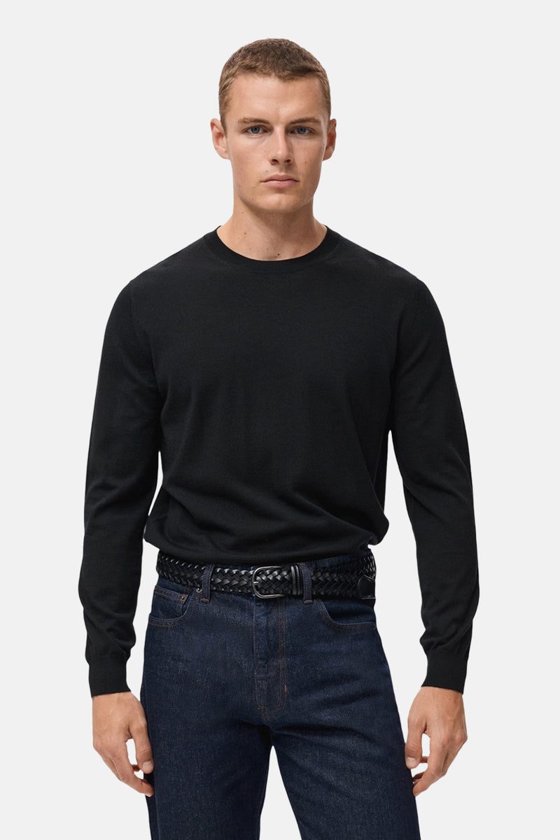 Zwarte rondehals trui van MANGO, gedragen met een donkere jeans en een gevlochten riem.