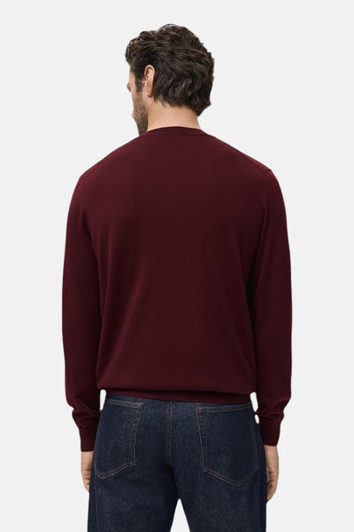 Bordeaux ronde hals trui van MANGO, van achteren gezien, gedragen met een donkerblauwe jeans.
