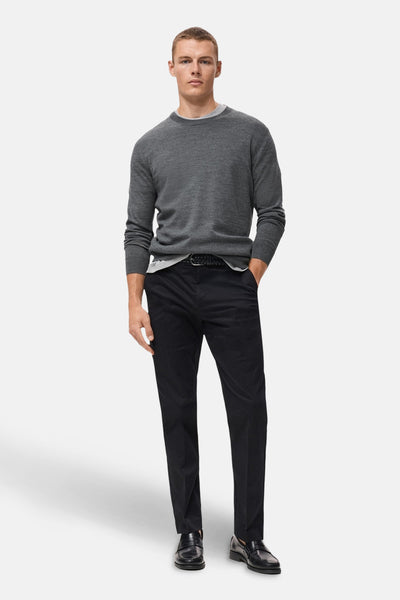 Grijze rondehals trui van MANGO, gedragen met een wit T-shirt en een zwarte broek.