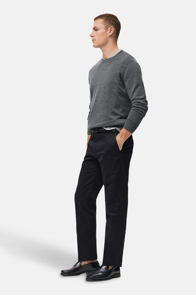 Grijze rondehals trui van MANGO, gedragen met een zwarte broek en leren loafers.