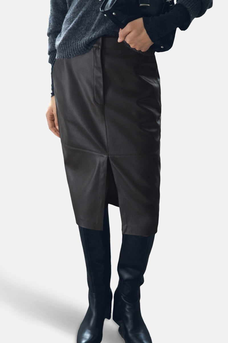 Jupe 3/4 marron en similicuir de MANGO, avec une fente avant et portée avec des bottes noires.
