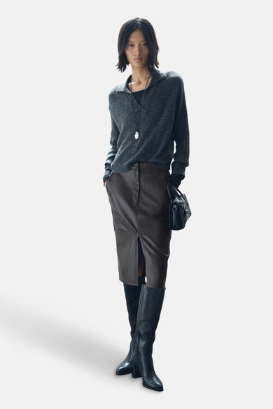 Jupe 3/4 marron de MANGO, avec une fente au milieu, portée avec des bottes noires et un pull gris.
