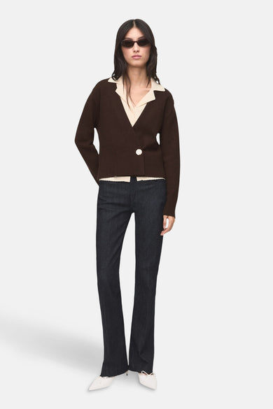 Gilet marron de MANGO, boutonné sur le côté et porté sur une chemise écrue à col blanc, avec un jean.
