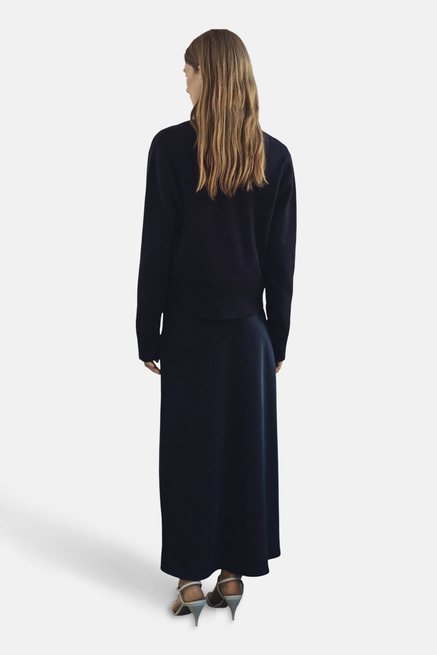 Gilet bleu de MANGO, porté avec une jupe longue bleue et des chaussures à talons ouverts, vue de dos.
