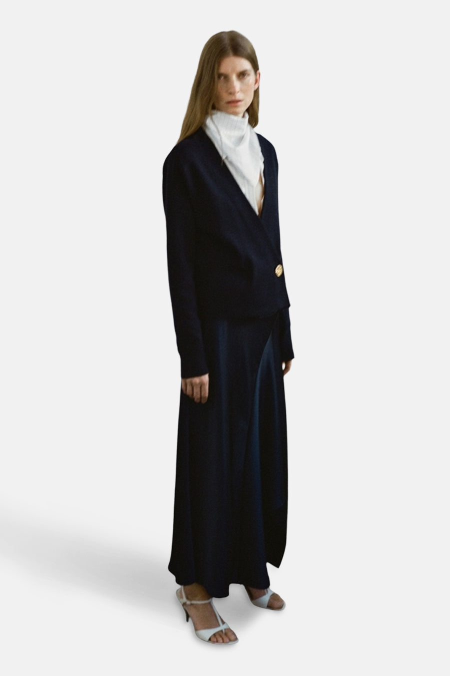 Gilet bleu de MANGO, porté avec une chemise blanche et une longue jupe foncée, avec des sandales à talons.
