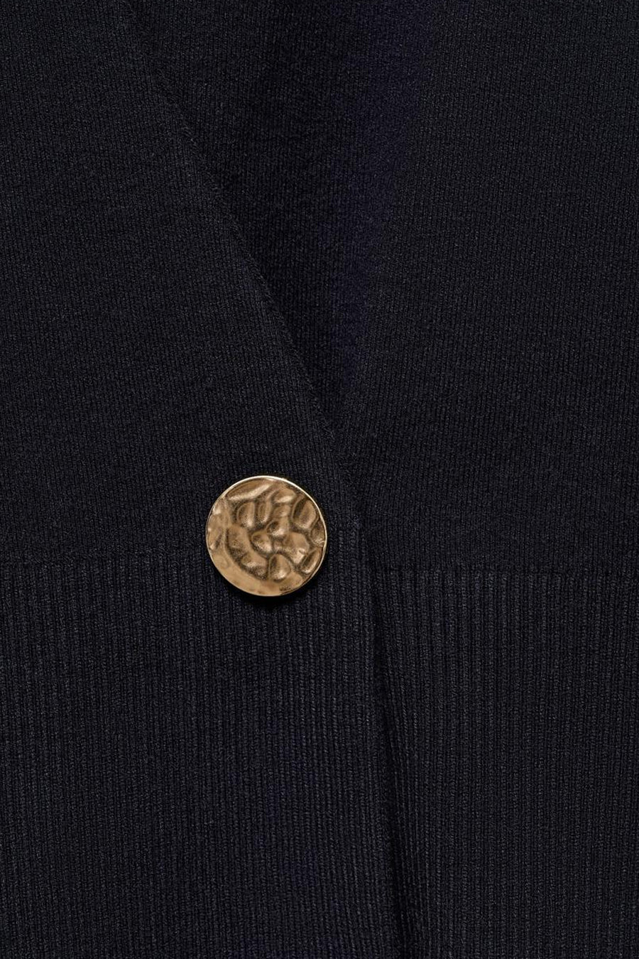 Gilet bleu en tricot de MANGO, avec une fermeture boutonnée dorée texturée.
