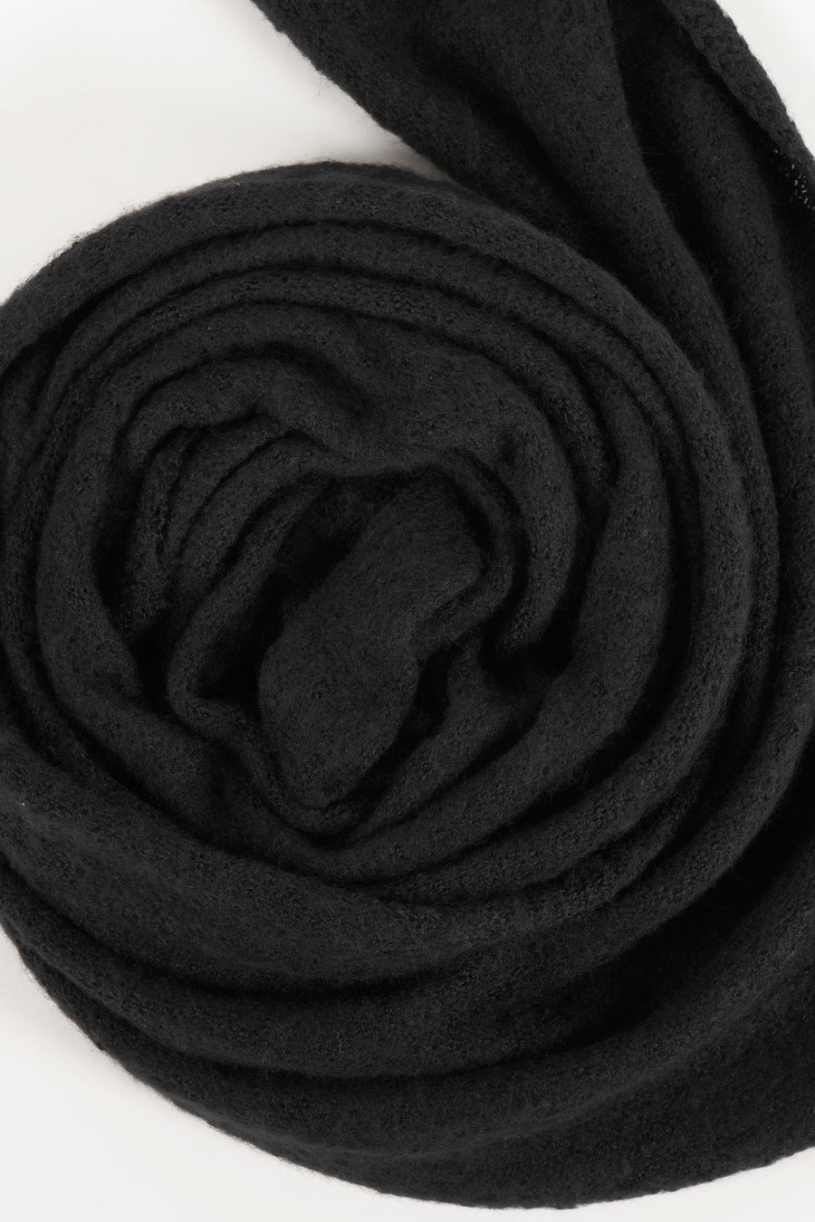 Écharpe noire enroulée de PIECES®, texture tricotée douce visible.