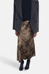 Jupe midi à imprimé animalier de MANGO, portée avec un pull noir et un manteau gris anthracite.