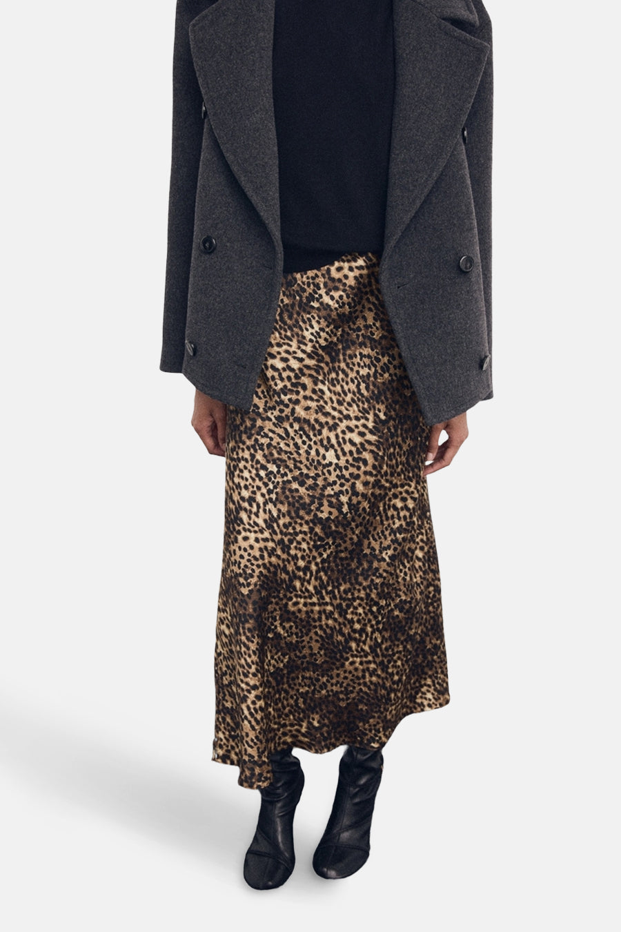 Jupe midi à imprimé animalier de MANGO, portée avec un pull noir et un manteau gris anthracite.