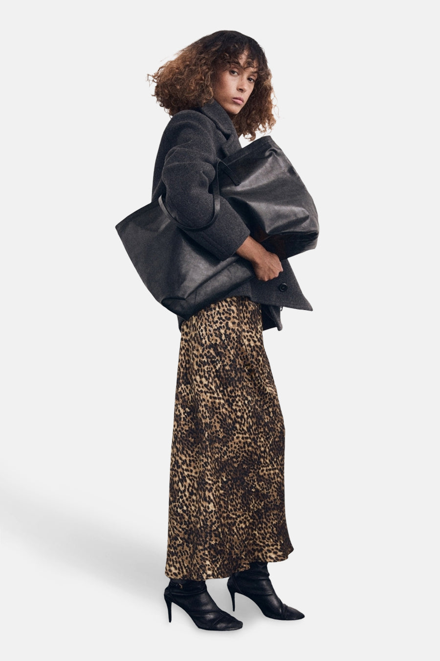 Jupe mi-longue à motif léopard multicolore de MANGO, portée avec un manteau gris et des bottines noires.
