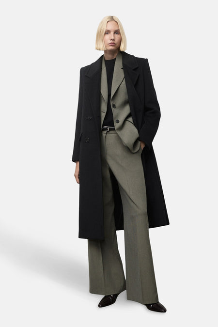 Pantalon vert MANGO, porté avec une ceinture noire, un blazer et un manteau longs noirs.