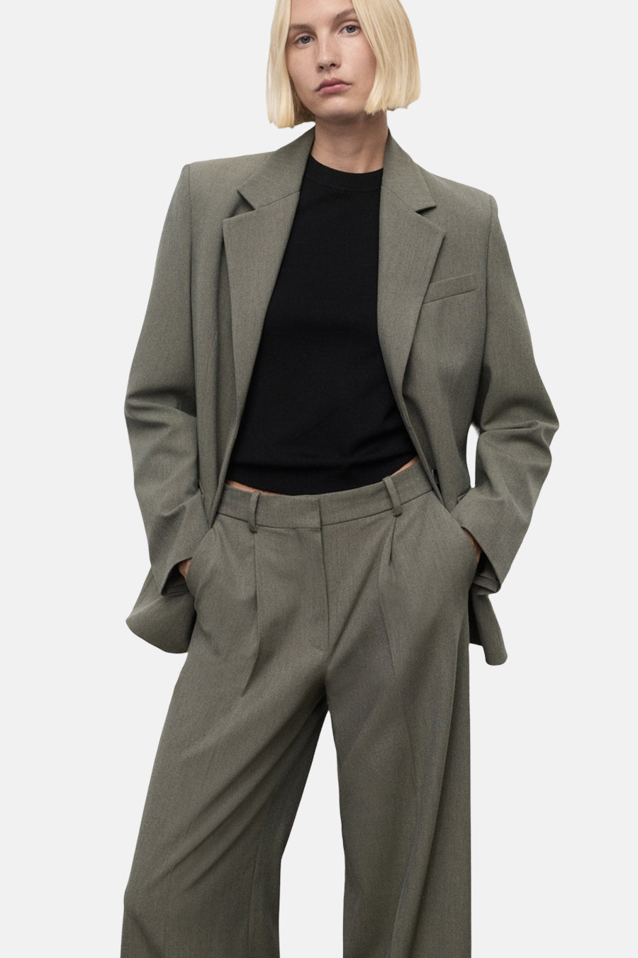 Groene broek van MANGO, met een wijde pasvorm en hoge taille, gedragen met een zwart T-shirt en een bijpassende blazer.