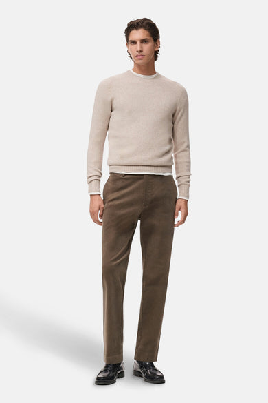 Pull à col rond beige de MANGO, porté sur un t-shirt blanc, avec un pantalon en velours côtelé marron et des mocassins noirs.