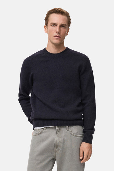 Pull à col rond bleu foncé de MANGO, porté avec un pantalon décontracté en denim gris