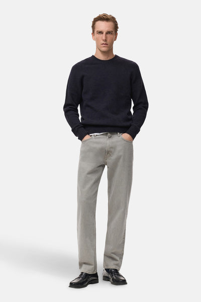 Pull à col rond bleu foncé de MANGO, porté avec un jean gris clair et des mocassins noirs.