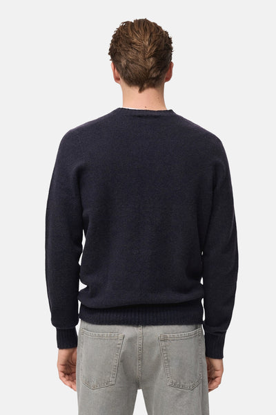 Pull à col rond bleu foncé de MANGO, vue de dos, porté avec un jean gris.
