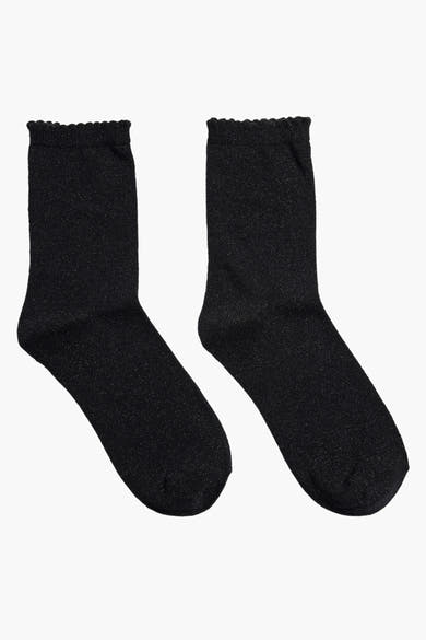 Chaussettes noires scintillantes de PIECES®, avec bordure ondulée, sur fond blanc.