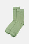 Groene sokken van PIECES®, in glanzende stof met golvende rand, schuin gepresenteerd.