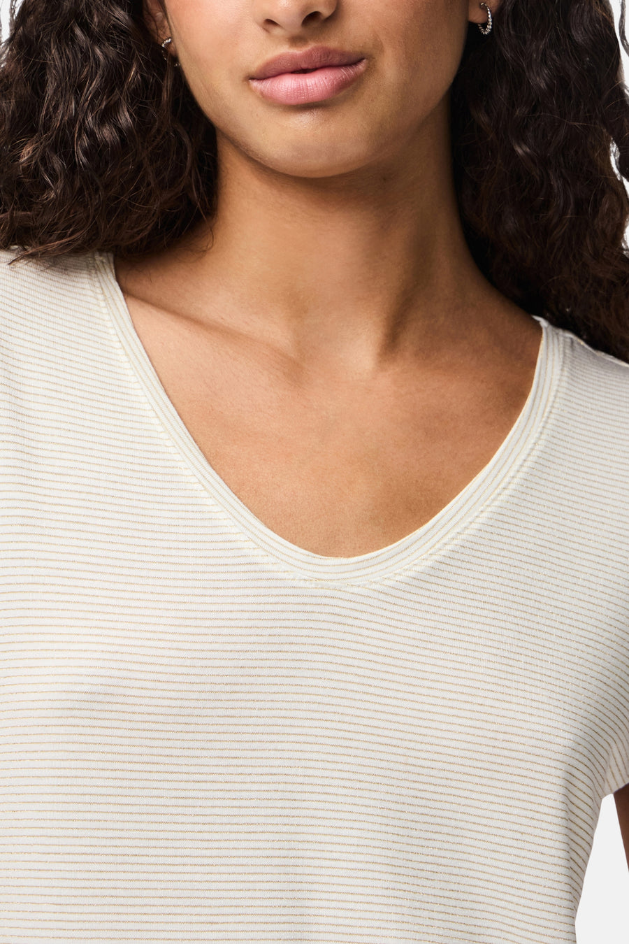 Wit T-shirt met gouden strepen van PIECES®, met een diepe V-hals en bruin krullend haar.