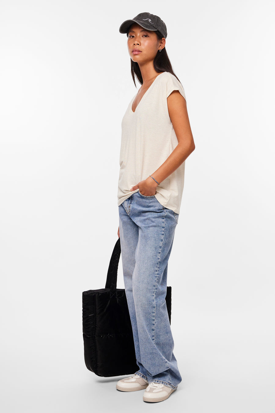 Wit T-shirt met fijne strepen van PIECES, gedragen met een wijde blauwe jeans, een zwarte tas en een pet.