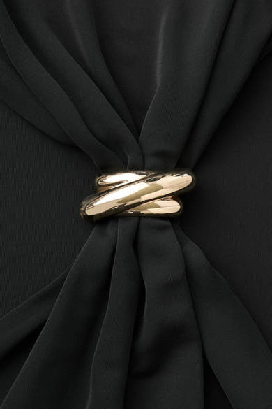 Zwarte gedrapeerde jurk van MANGO, versierd met een gevlochten gouden ring in het midden.
