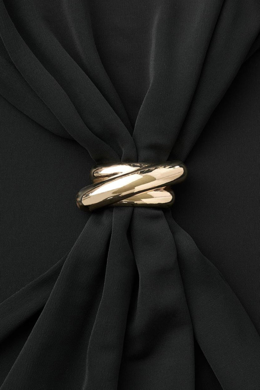 Zwarte gedrapeerde jurk van MANGO, versierd met een gevlochten gouden ring in het midden.