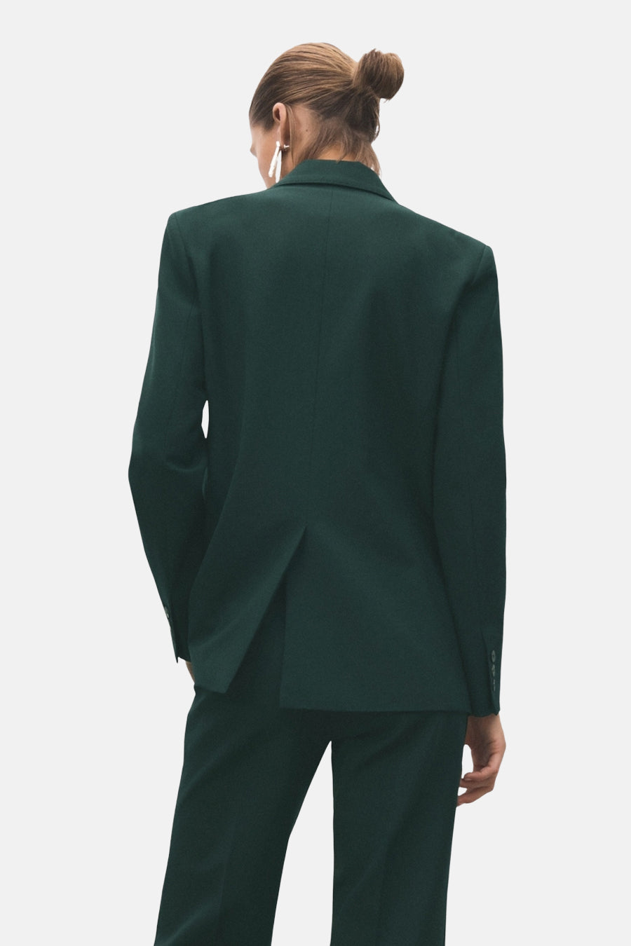 Donkerblauwe blazer van MANGO, achtergezicht, met gestructureerde snit en ingesneden revers, gedragen met bijpassende broek.