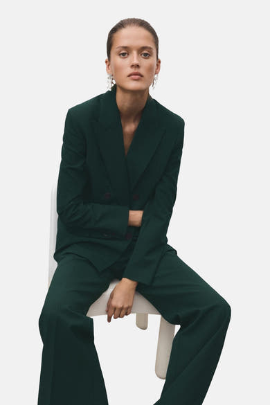 Groene blazer van MANGO, gedragen met een bijpassende broek en lange hangende oorbellen.
